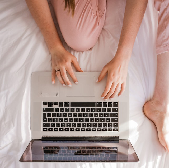 Woman on bed with laptop in front of her